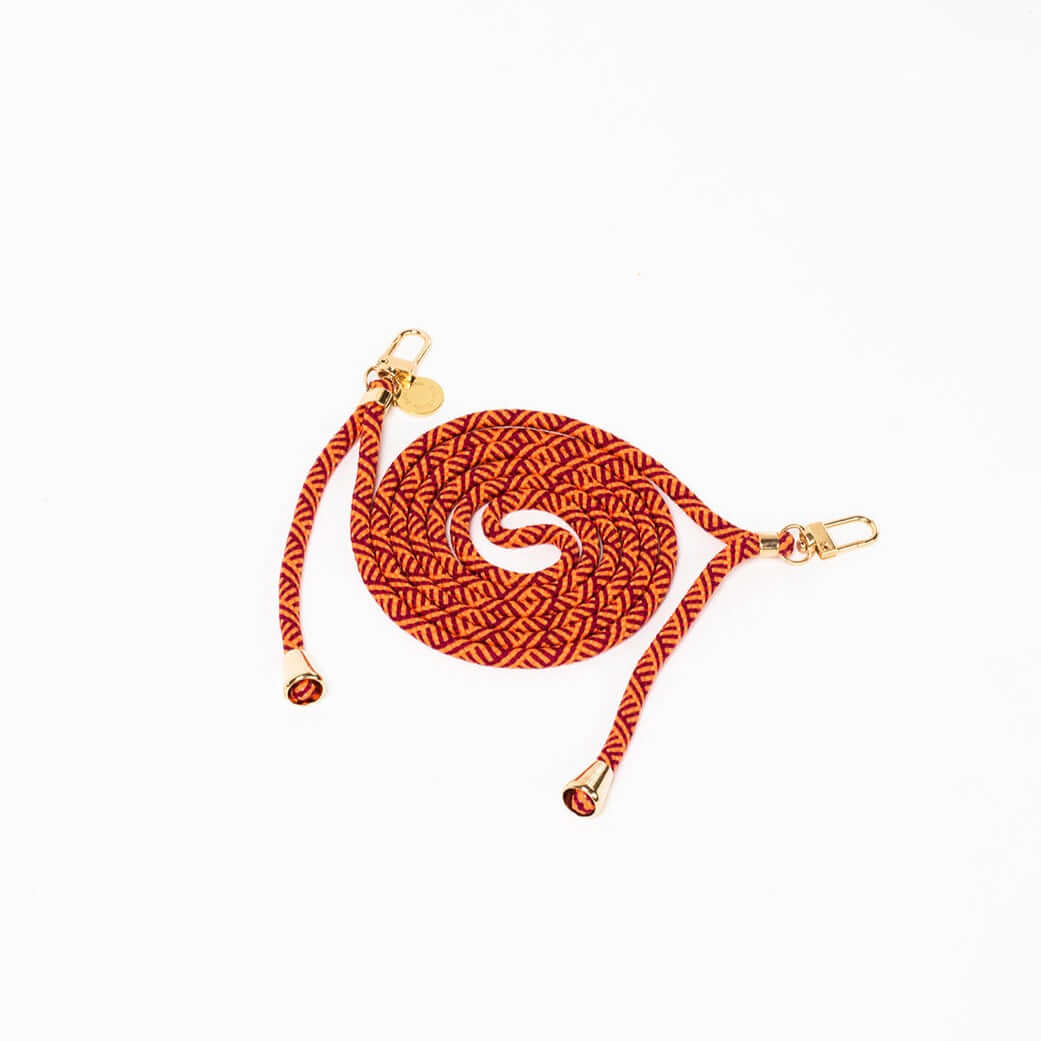 Orange and burgundy patterned Multi Colorful PHONE CORD coiled with gold-tone hardware on white.