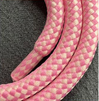 Extreme close-up of the pink and white woven texture of a Multi Colorful PHONE CORD on gray fabric.