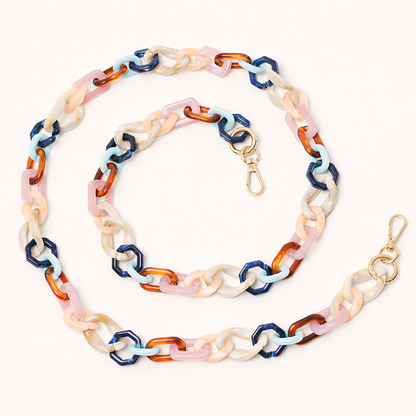 A coiled acrylic link phone chain in navy, light blue, tortoiseshell, and cream tones with a gold clasp, shown on a cream background.