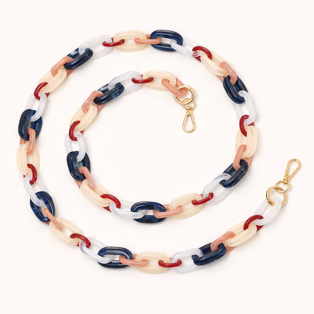 A coiled acrylic link phone chain in navy, red, cream, and clear tones with a gold clasp, shown on a cream background.