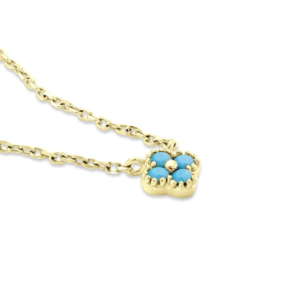 The Nessa NECKLACE in gold with turquoise stones, a close-up angled view of the clover-shaped cluster on its chain.