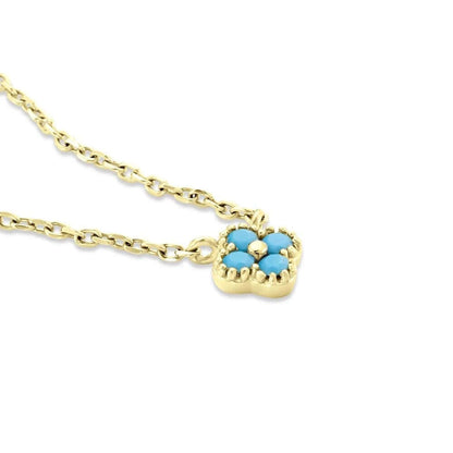 The Nessa NECKLACE in gold with turquoise stones, a close-up angled view of the clover-shaped cluster on its chain.