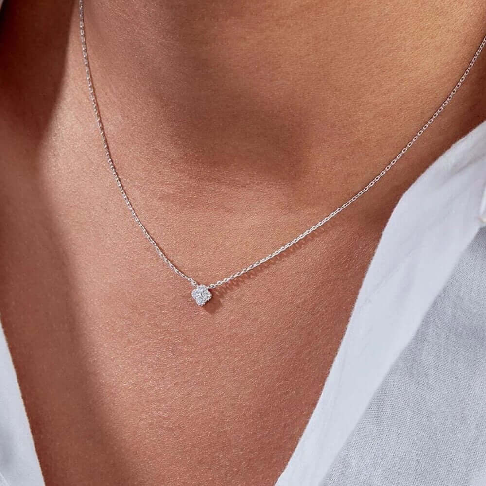 The Nessa NECKLACE in silver worn at the neckline, the sparkling clover cluster pendant above a white button-up shirt.