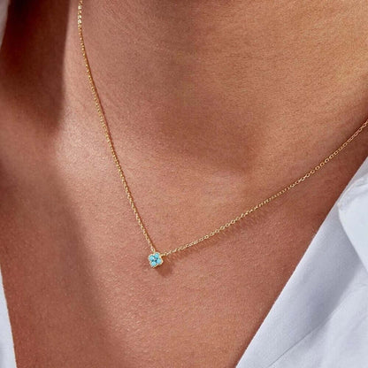 The Nessa NECKLACE in gold with turquoise stones worn at the neckline, the clover cluster pendant on a fine chain.