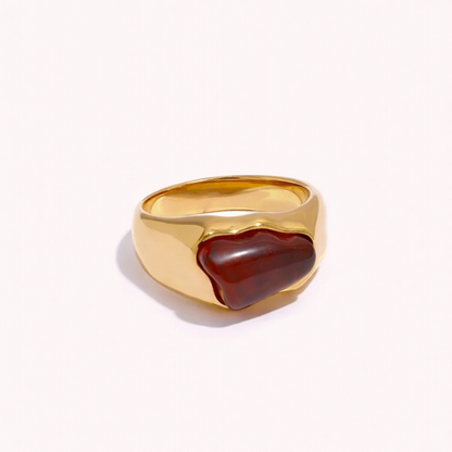 Gold signet-style New Fashion RING set with an irregular amber cabochon stone, shown at an angle on a cream backdrop.