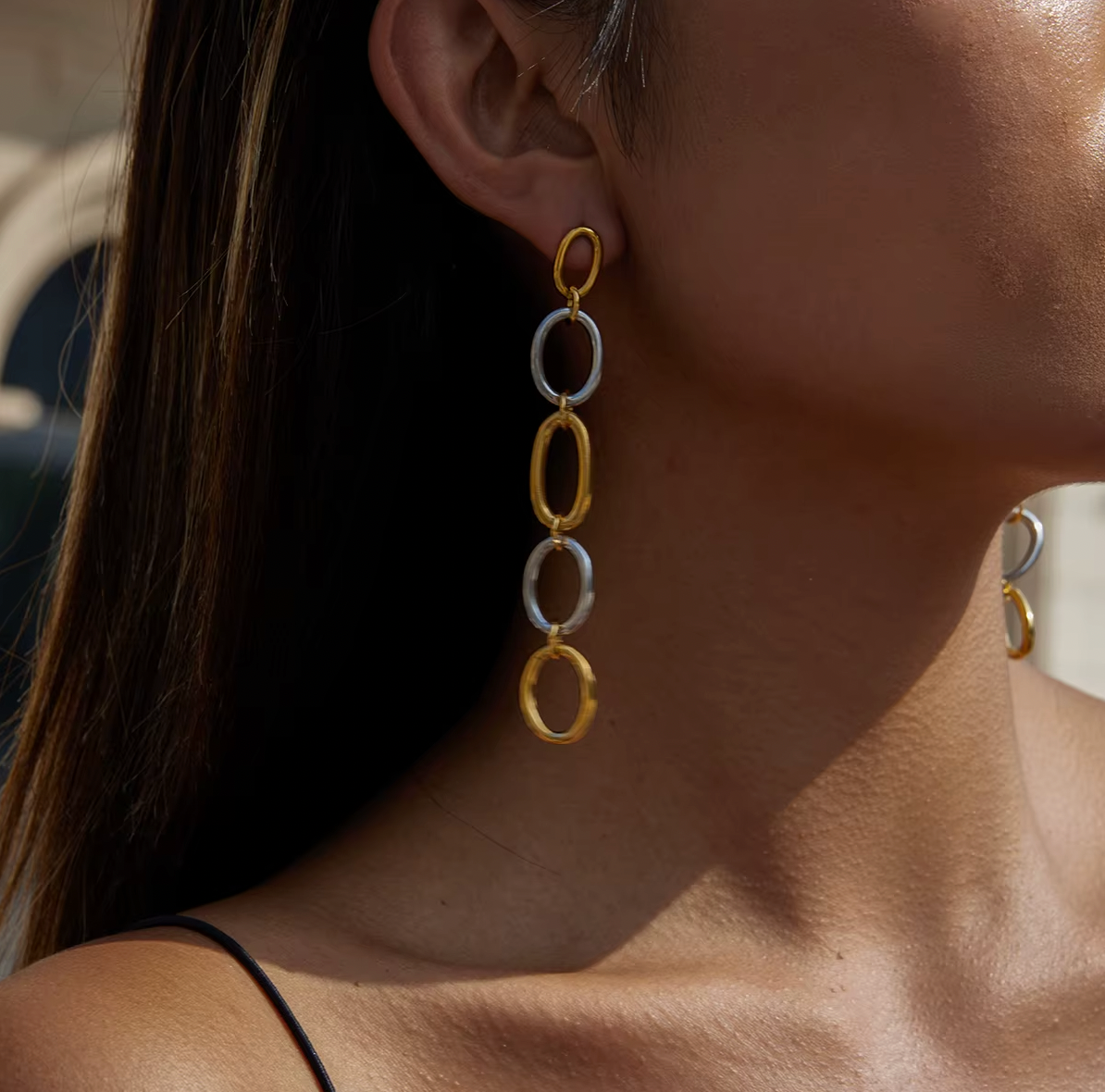Worn on a model's ear, the No Apologies EARRINGS trail their two-tone oval link chain along the neck.