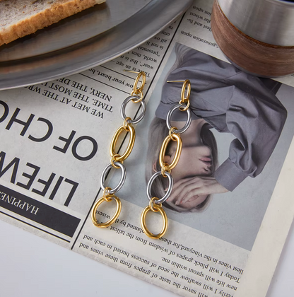 The No Apologies EARRINGS rest on an open magazine beside a plate and mug, showing their link chain.