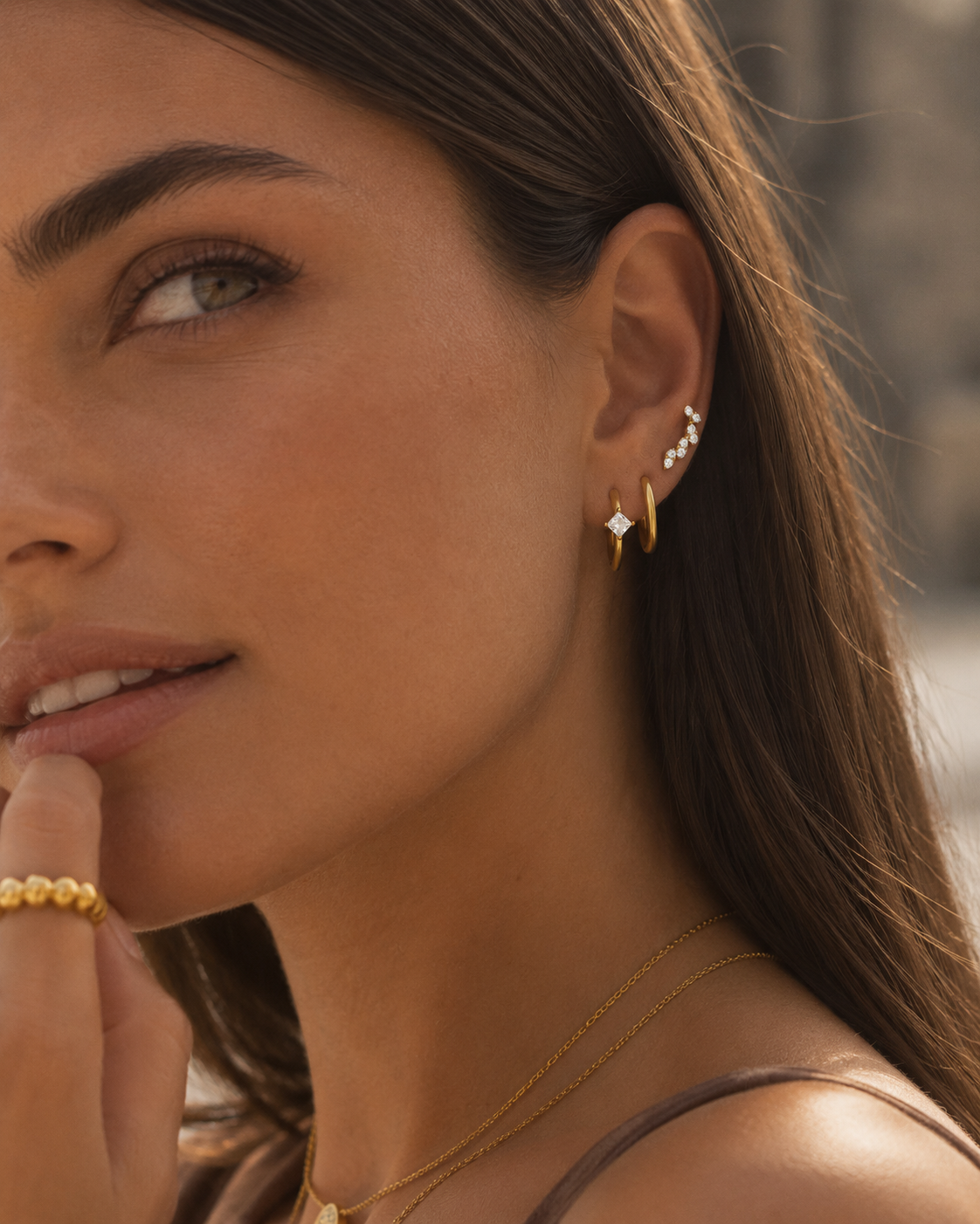 Model's ear wearing the gold Folie à Trois Odile SET stacked with a pavé cuff, a hoop set with a square crystal and a climber stud.