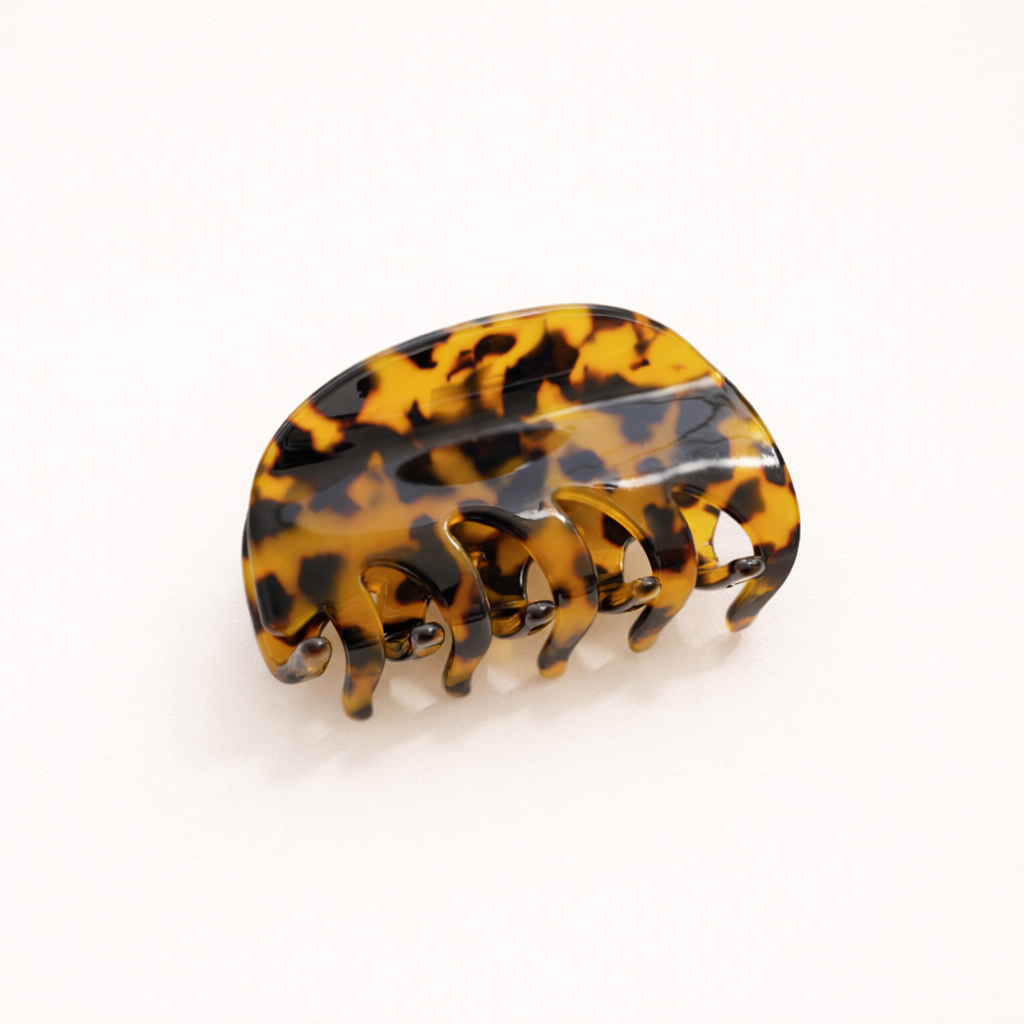 A single amber and black tortoiseshell acetate hair claw clip shown on a plain background.