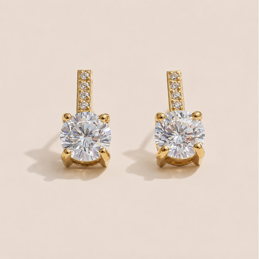Gold stud earrings with a round white zirconia solitaire below a pavé bar on a cream backdrop — Folie à Trois Orbit EARRINGS