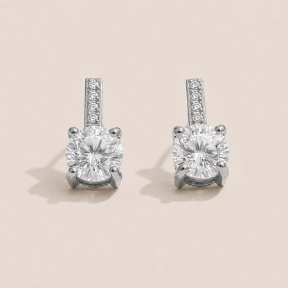 Silver stud earrings with a round white zirconia solitaire below a pavé bar on a cream backdrop — Folie à Trois Orbit EARRINGS