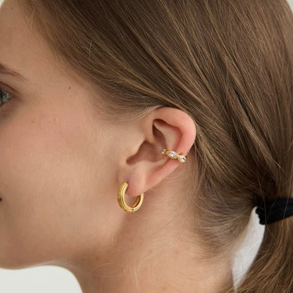 Overdrive ear cuff worn on the cartilage with marquise crystals catching the light above a ribbed gold hoop earring.