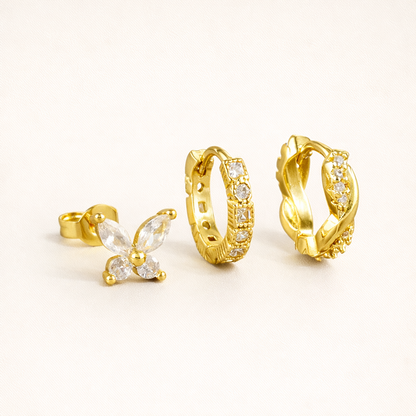 Palloma Set of gold jewelry, a butterfly stud, a pave hoop with a striped texture, and a twisted braid hoop with stones.