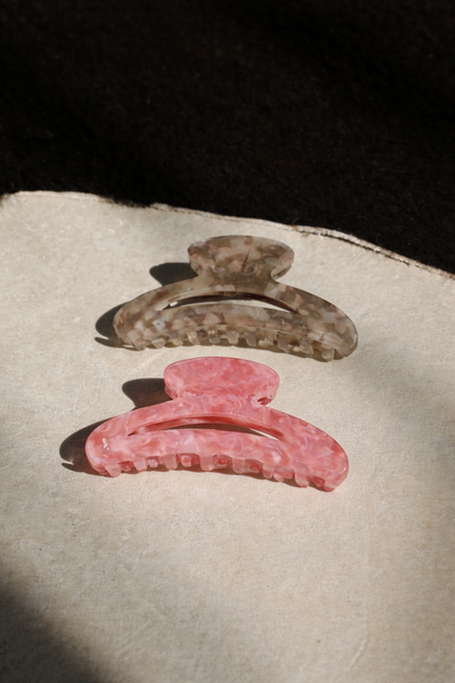 Palm Springs HAIR CLIP's grey and pink marbled claw clips laid on a paper card in sunlight.