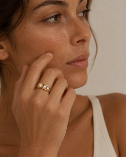 Model wears a gold Pavé Line RING with three graduated white stones, hand raised to the cheek — Folie à Trois