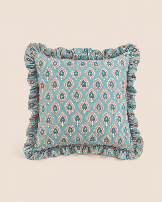 Teal-blue Peacock Blue Square cushion patterned with rust-red paisley teardrops and finished with a soft ruffled edge on a cream backdrop.