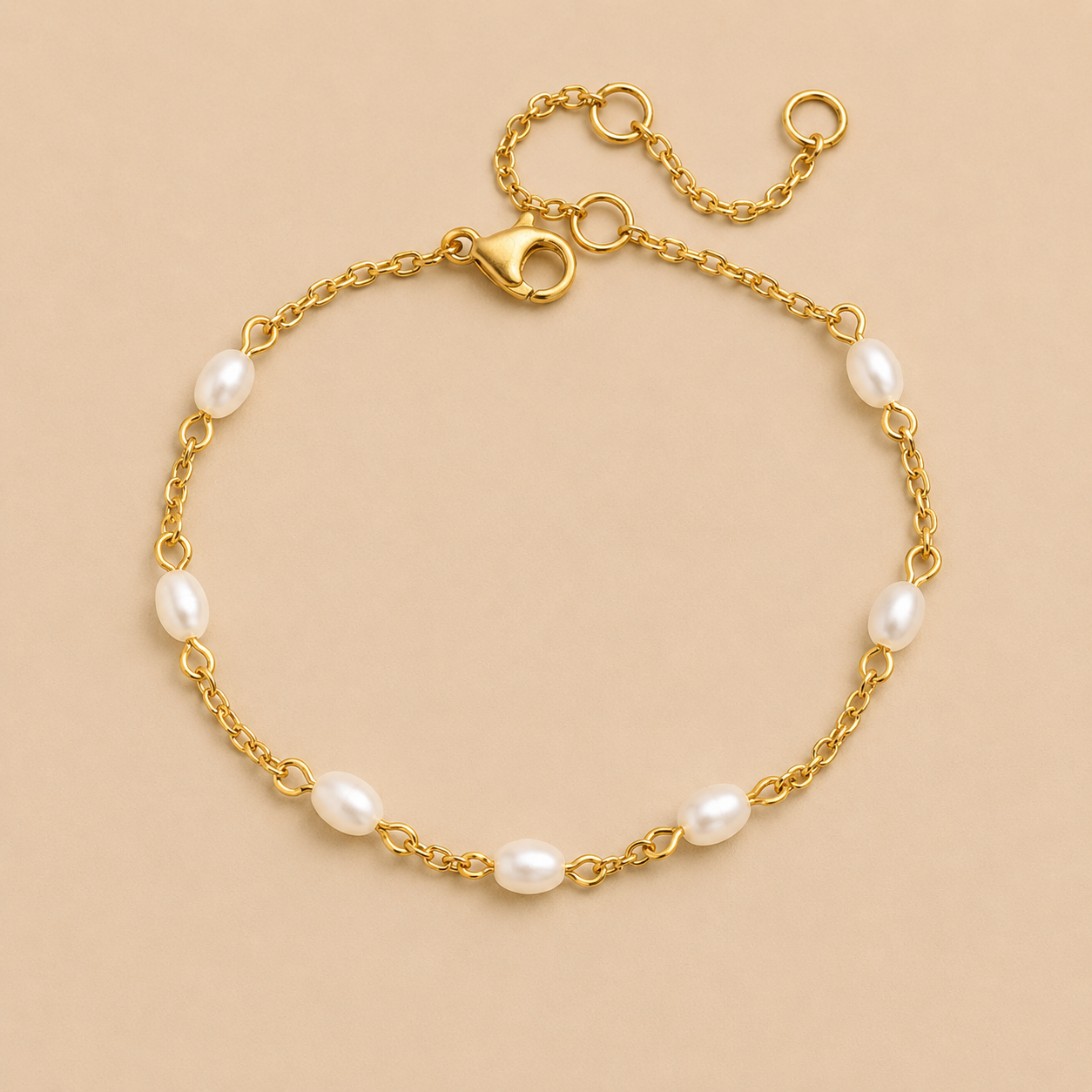 Perle BRACELET in gold with small oval freshwater pearls spaced along a delicate chain, shown flat on a beige background.
