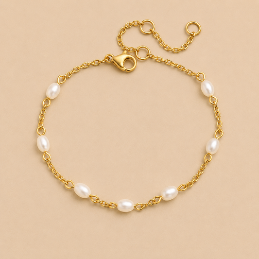 Perle BRACELET in gold with small oval freshwater pearls spaced along a delicate chain, shown flat on a beige background.