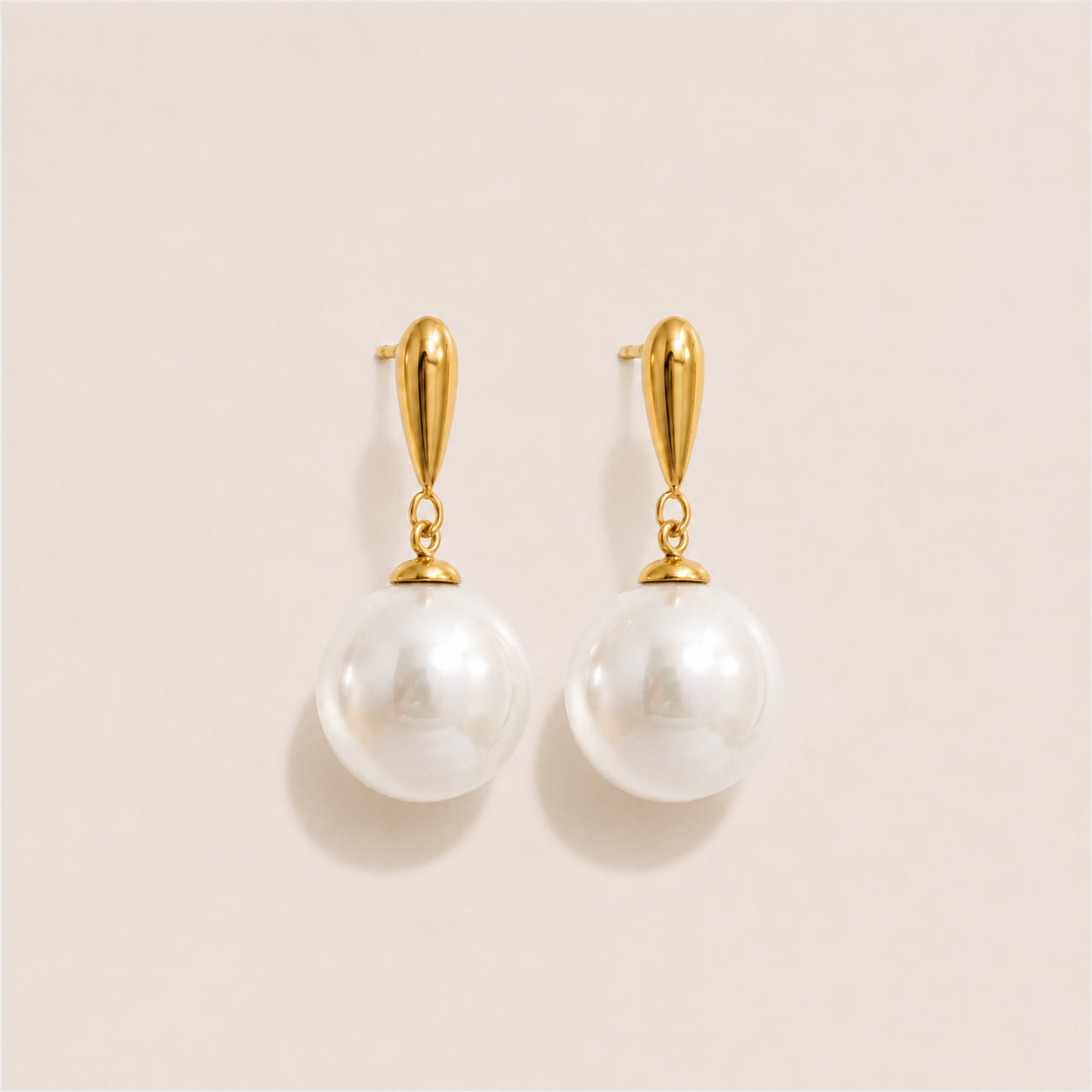 Gold drop earrings with a teardrop post and a large round white pearl on a cream backdrop — Folie à Trois Perle Drop EARRINGS