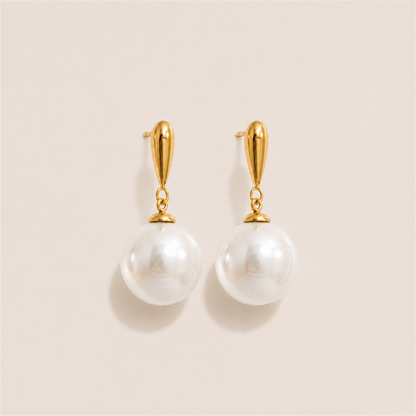 Gold drop earrings with a teardrop post and a large round white pearl on a cream backdrop — Folie à Trois Perle Drop EARRINGS
