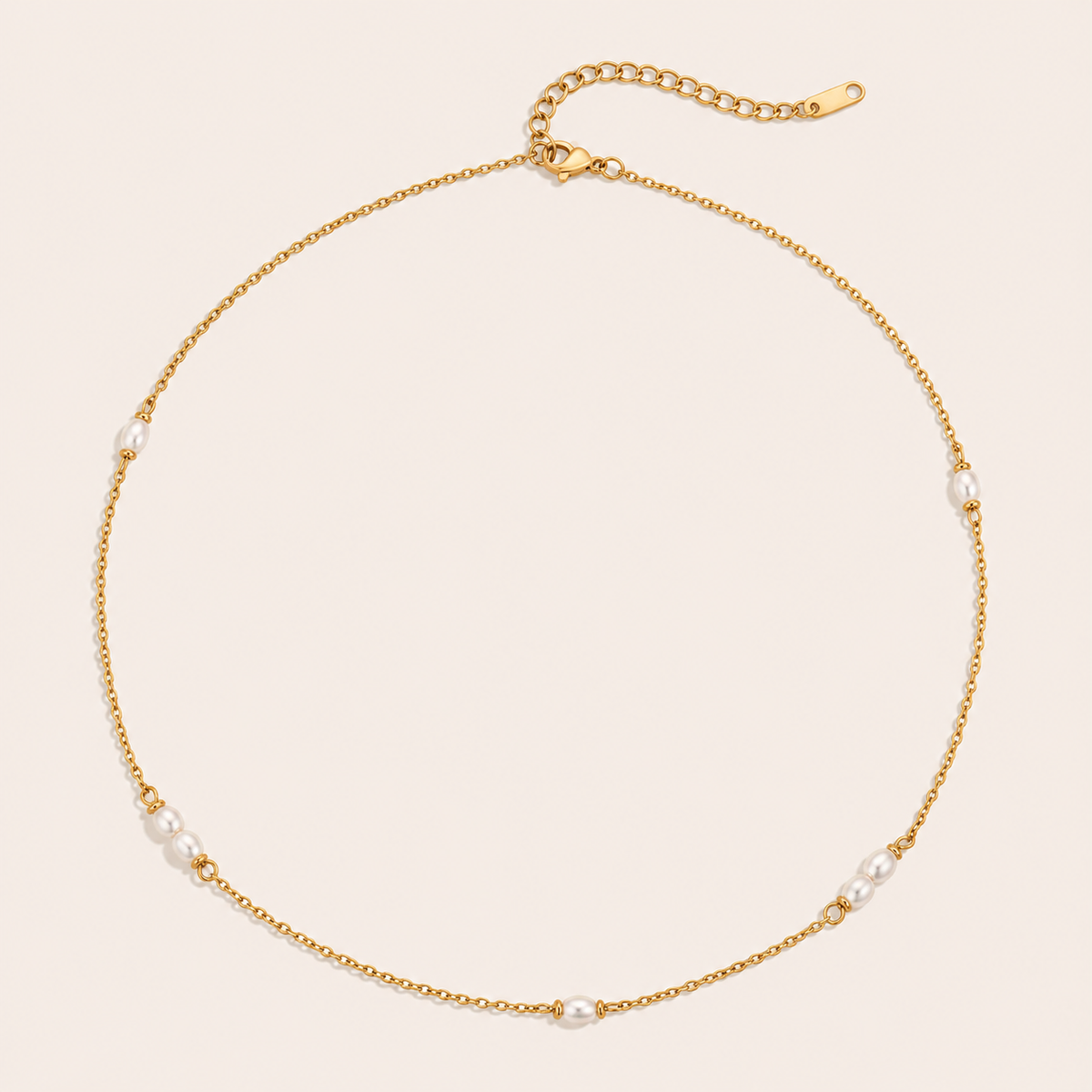 Gold satellite chain necklace with small pearl stations from the Perle NECKLACE design, laid flat on beige.
