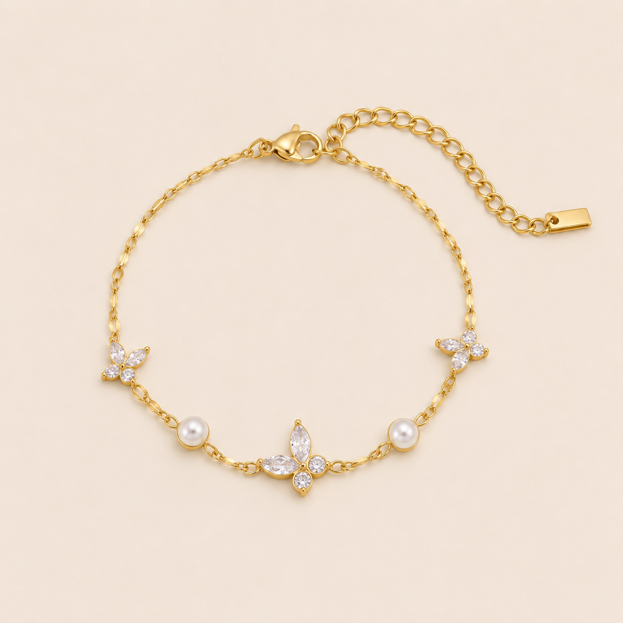 Peschici BRACELET in gold with crystal clover charms and white pearl beads set along a delicate chain, shown flat.