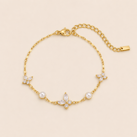 Peschici BRACELET in gold with crystal clover charms and white pearl beads set along a delicate chain, shown flat.