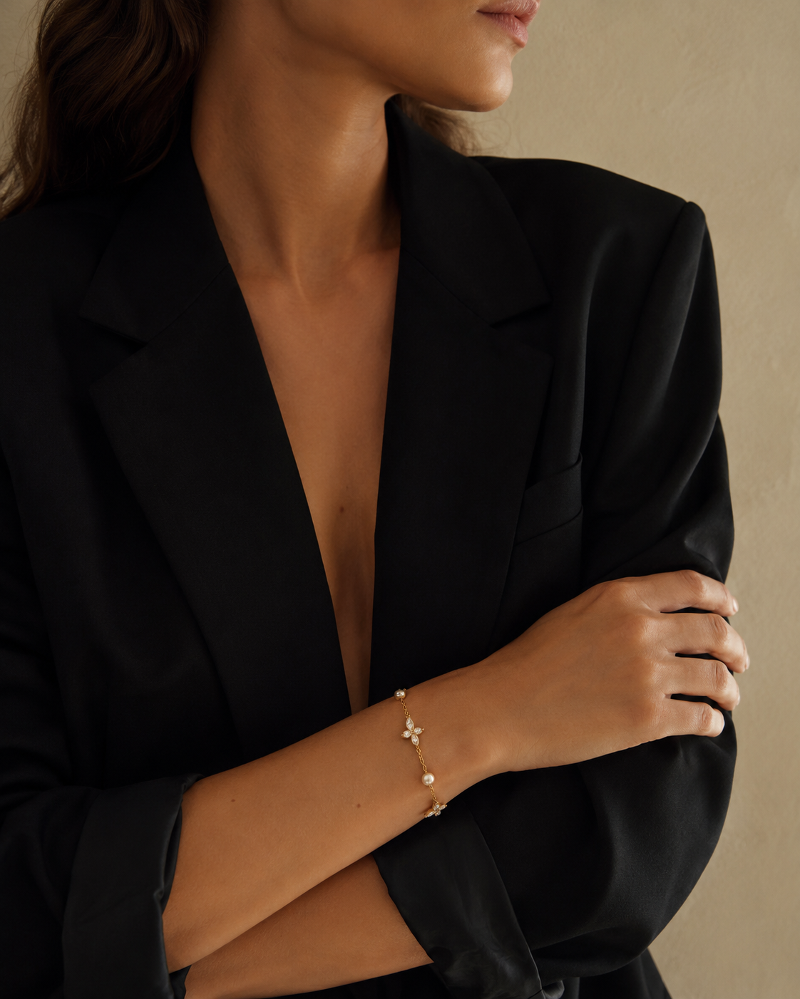 Peschici BRACELET worn on the wrist with pearl and crystal clover details, model in a black blazer with arms crossed.