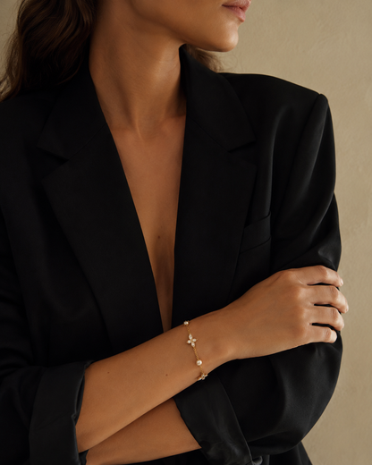 Peschici BRACELET worn on the wrist with pearl and crystal clover details, model in a black blazer with arms crossed.