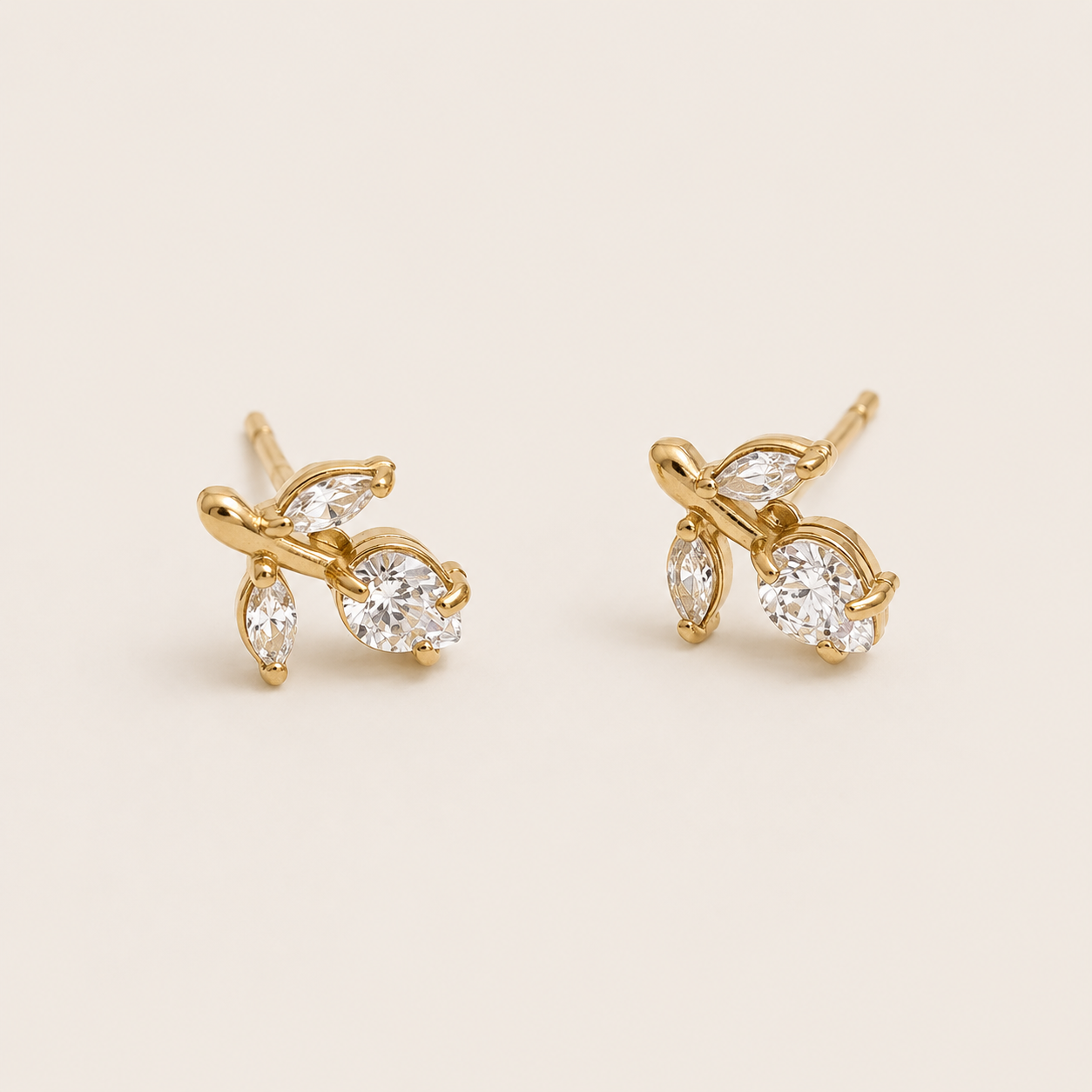 Gold vine-shaped stud earrings clustering marquise and round white zirconia stones on a cream backdrop — Folie à Trois Petiole EARRINGS