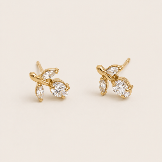 Gold vine-shaped stud earrings clustering marquise and round white zirconia stones on a cream backdrop — Folie à Trois Petiole EARRINGS