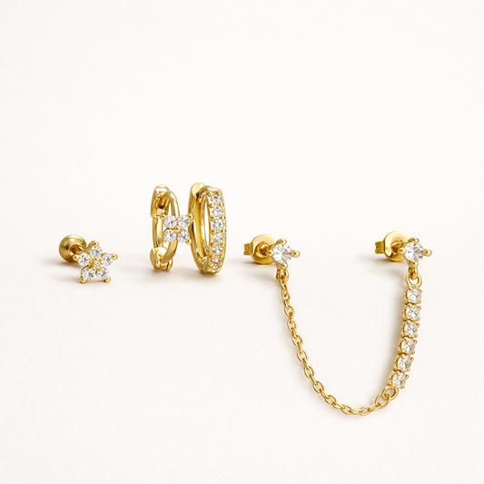 Pixie Set of four gold pieces: a crystal flower stud, a pave huggie hoop, and a pair of studs joined by a delicate crystal chain.