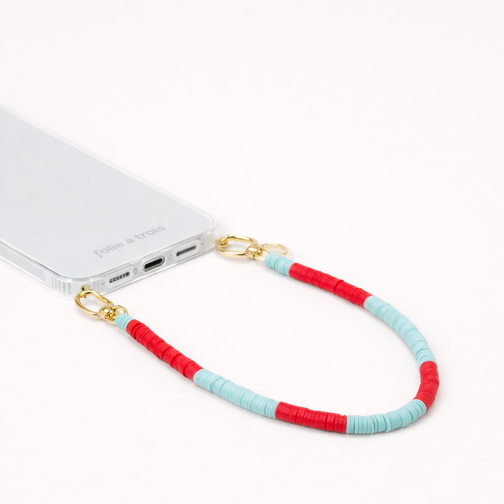 Red and turquoise heishi bead Poppy SHORT PHONE CORD clipped to a clear phone case with gold hardware.