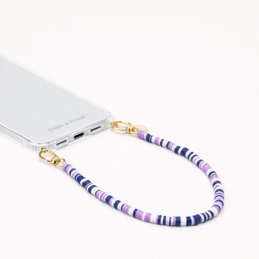 Navy, lavender, and white heishi bead Poppy SHORT PHONE CORD clipped to a clear phone case with gold hardware.