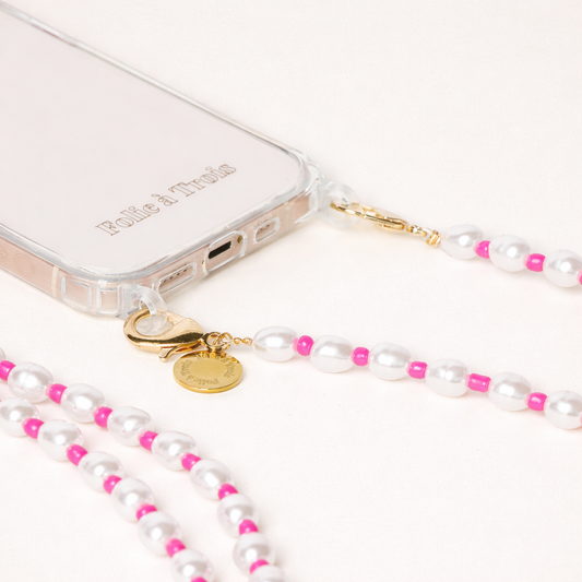 Close-up of the gold clasp and charm on a white pearl and pink bead Posy Pearl LONG PHONE STRAP attached to a clear phone case.