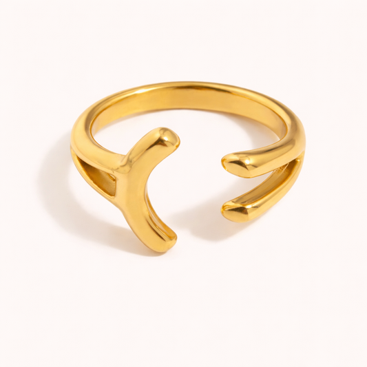Open gold ring with an asymmetric branching, wishbone-like split design, shown on a cream backdrop — Folie à Trois Power Play RING.