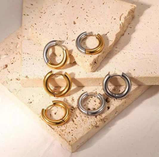 Radiant Bliss Earrings display three pairs of chunky tube hoops in gold and silver, arranged on a stone slab.