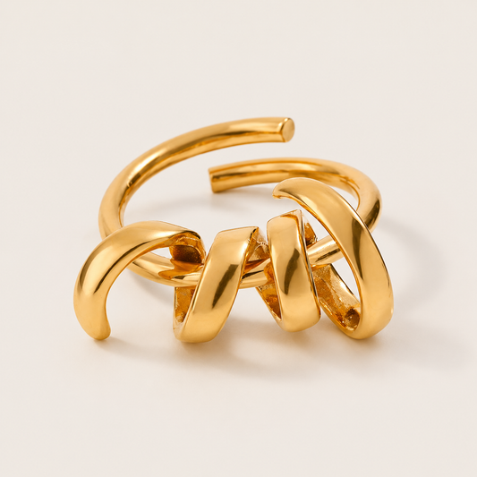 Gold ring with a spiral coil of wire wound around an open band, shown in close-up on a cream backdrop — Folie à Trois Rebel Shine RING.