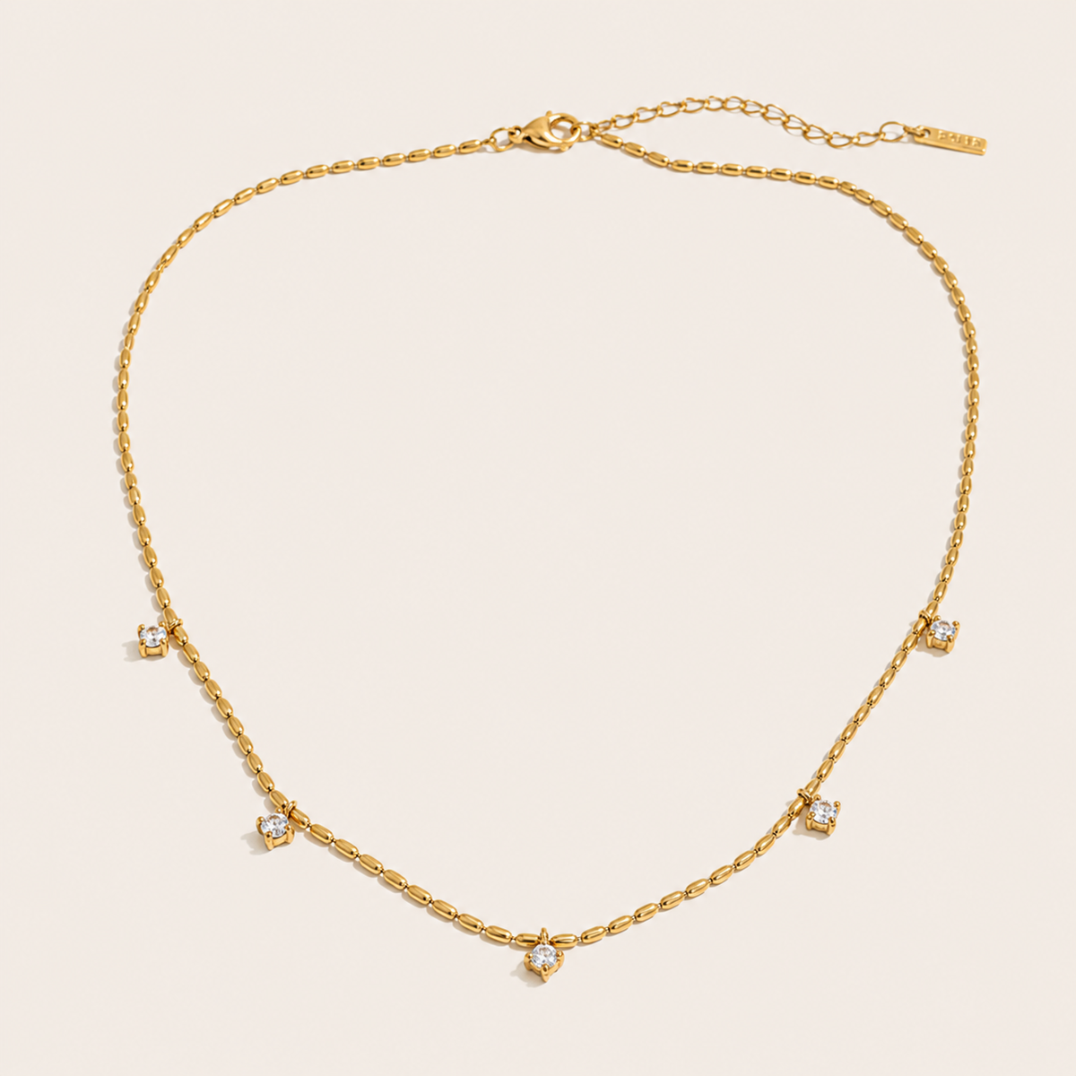 Gold station necklace with five round white zirconia charms spaced along a fine beaded chain — Folie à Trois Reverie NECKLACE.