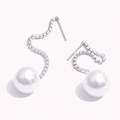 Rhea Earrings in a silver-tone finish, the wavy crystal-lined chain curling down to a glossy white pearl at the end.