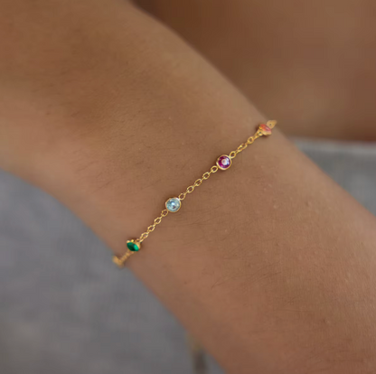 A single gold Riva BRACELET on the wrist, its fine chain dotted with green, aqua, fuchsia and orange bezel-set gemstones.