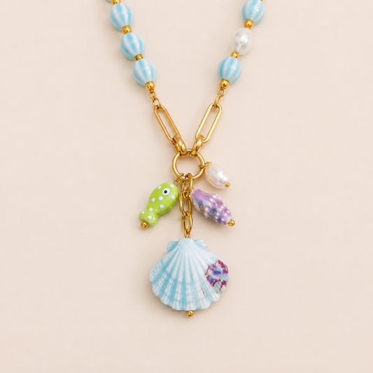 Rivage NECKLACE with blue and pearl beaded chain holding a scallop shell, purple shell, pearl and enamel fish charm.