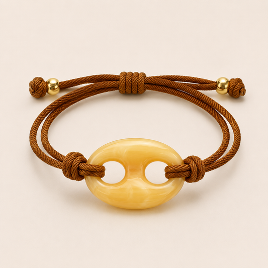 Riviera BRACELET in butter yellow resin, an oval clasp on a brown cord with adjustable gold beads, shown flat.