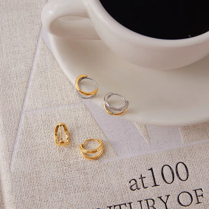 Close-up flat lay of Roadtrip Earrings on a book page next to a coffee cup, showing the chunky two-tone hoop design.