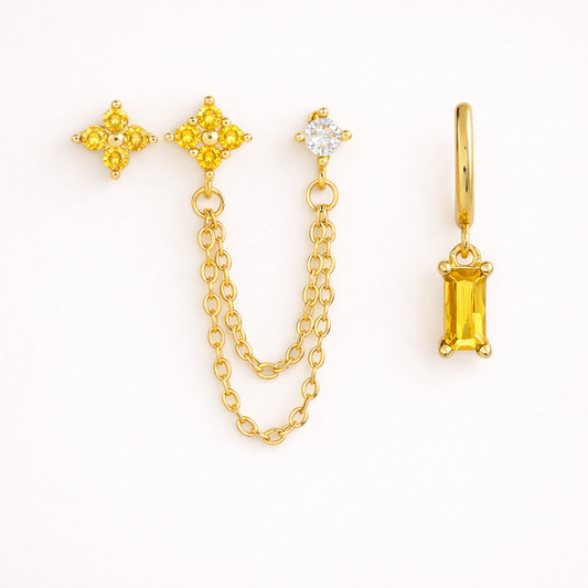 Robbie SET pairs two star studs joined by draped chain and a clear stud with a hoop dangling a yellow baguette stone.