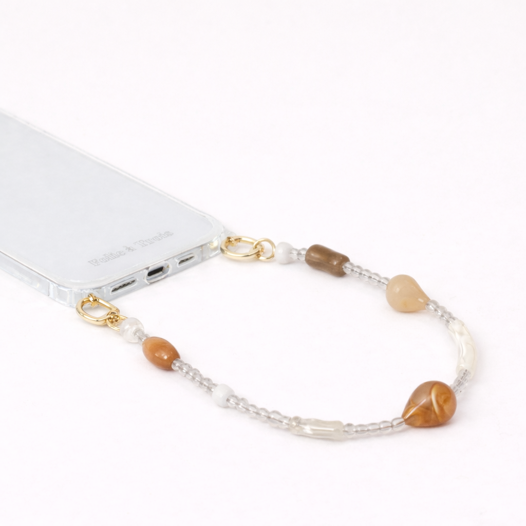 Mixed stone teardrop beaded Romee short phone strap clipped to a clear phone case, close-up view.