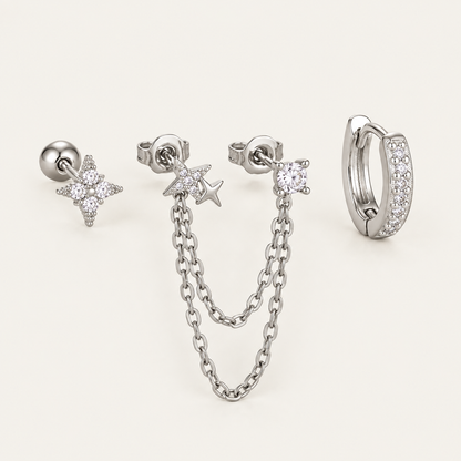The Folie à Trois Romy SET in silver: a star stud, a star chain-drop earring, a round bezel stud and a pavé huggie hoop.