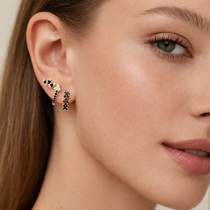 Rosalia Set worn on the ear in gold, a flower stud beside two pave hoops set with black onyx stones.