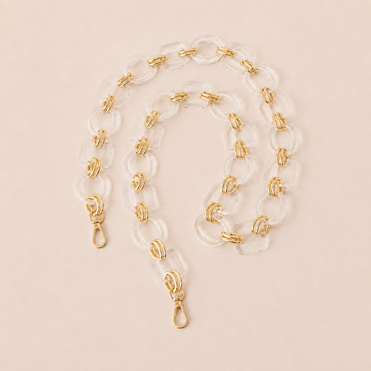 Clear acrylic link phone chain with gold connectors coiled on cream — Folie à Trois Rowan wholesale phone chain