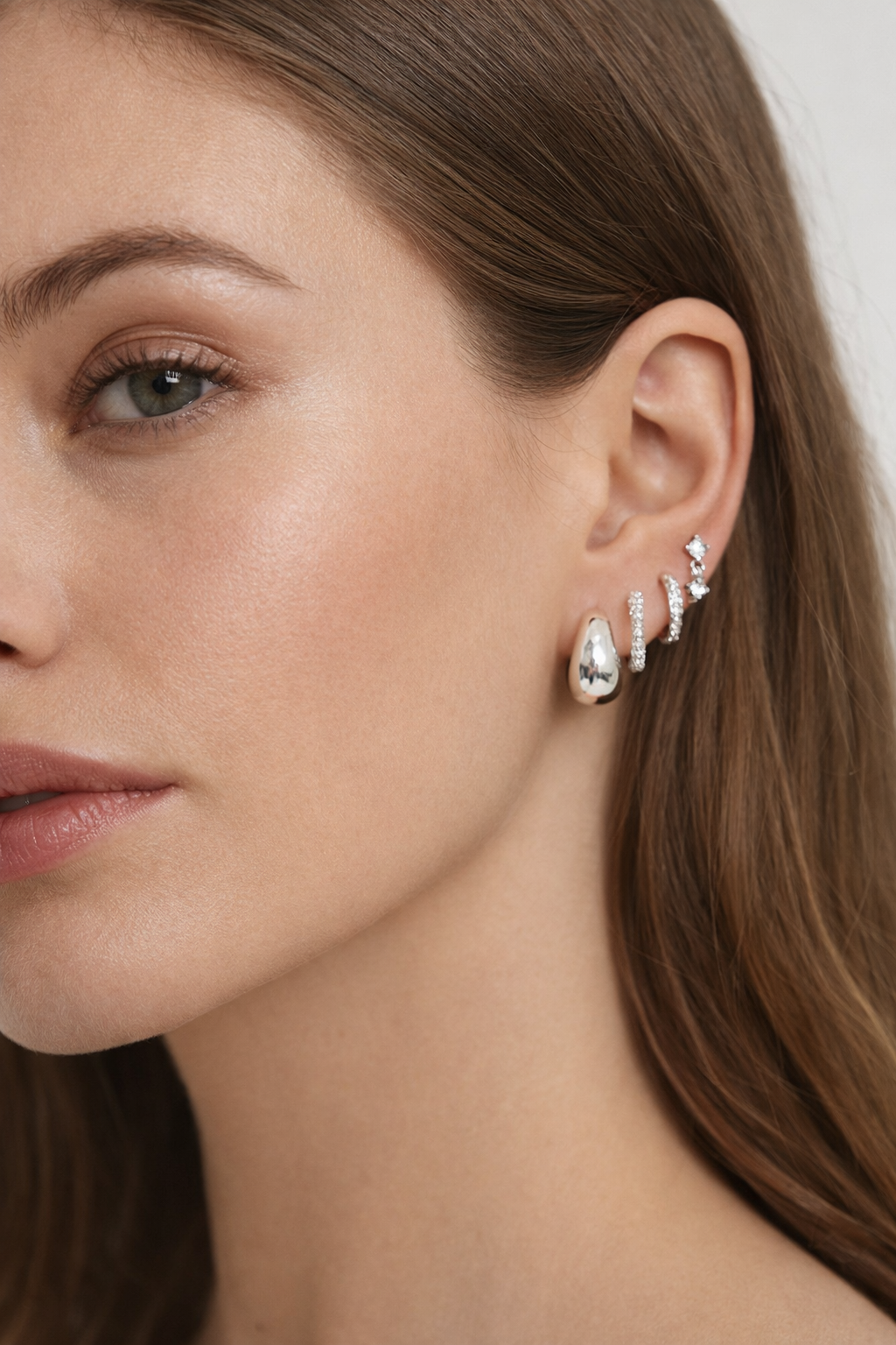 Roxy Set in silver tone worn on the ear, showing a chunky teardrop hoop stacked with pave and plain hoops.